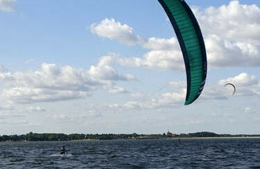 Kitesurferzy na wodach Zalewu Mietkowskiego, w tle kości&oacute;ł i malownicze...