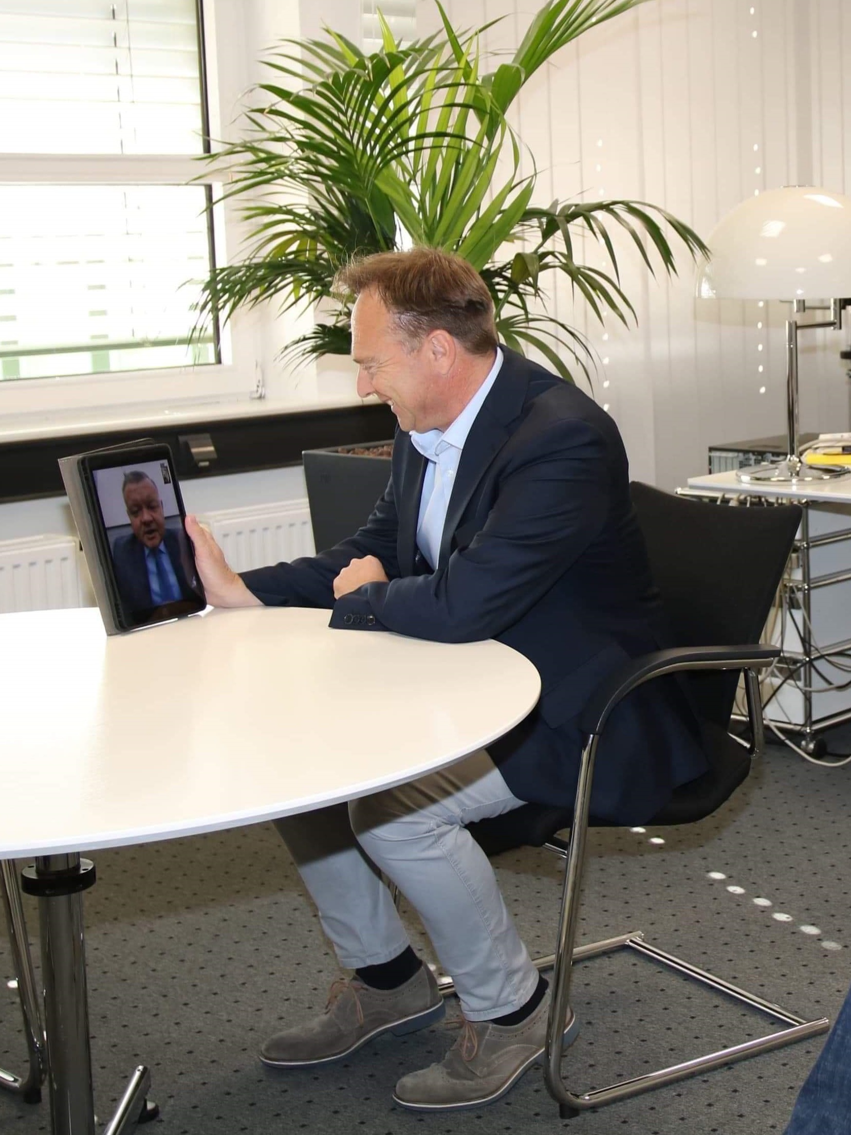 Na zdjęciu widać starostę Kai Zwickera siedzącego przy stole z tabletem w ręku, prze który prowadzi wideokonferencję ze starostą Romanem Potockim